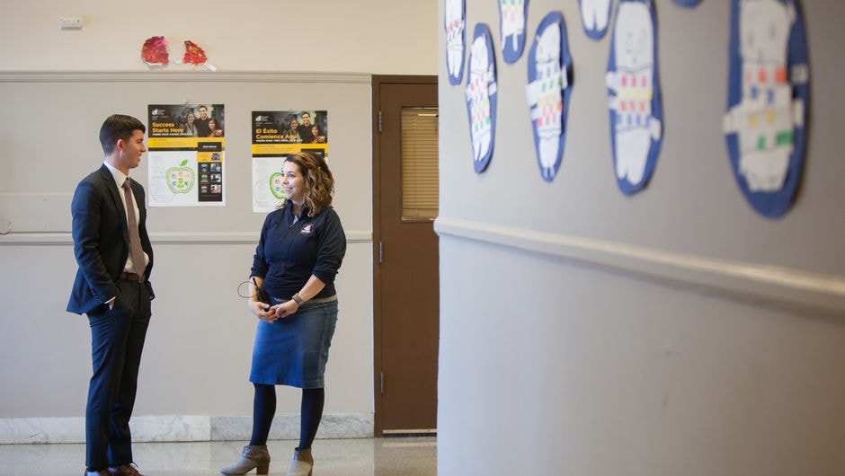 Two alumni school leaders stand in a hallway