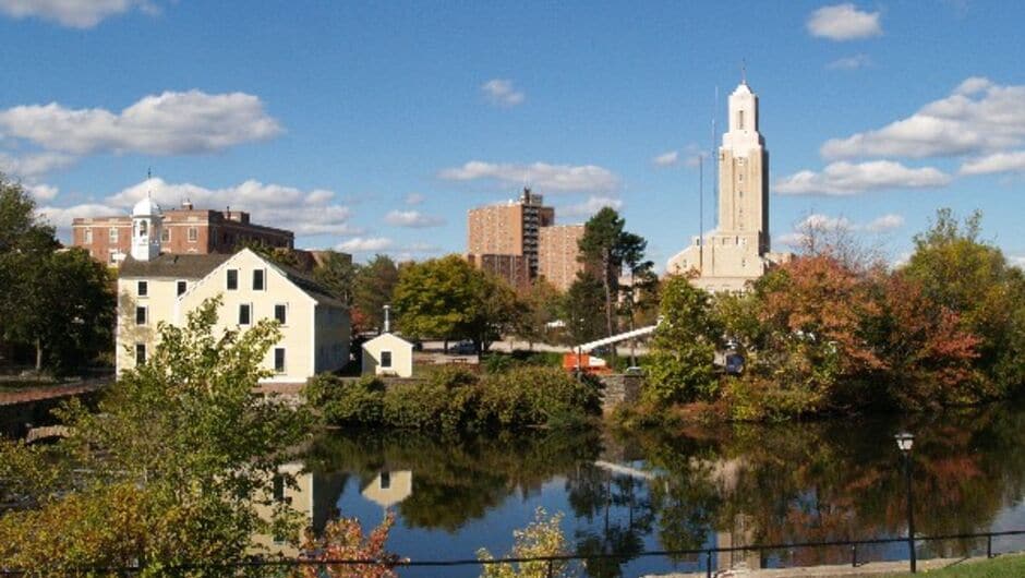 A view of a river, fall color trees, and historic buildings in Pawtucket, RI.