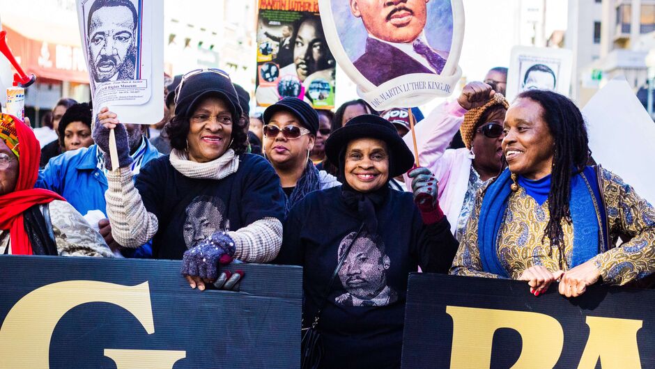 People walk in a parade with photos of MLK